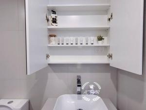 Baño blanco con lavabo y aseo en City View Lovely 1BD Apartment @ CBD, en Canberra