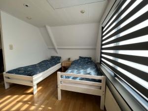 Duas camas num pequeno quarto com uma janela em Vakantiehuis centrum Schagen nabij zee / strand em Schagen