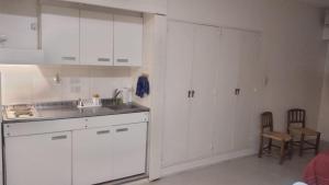 una cocina con armarios blancos, fregadero y sillas en Juncal Apartment en Buenos Aires