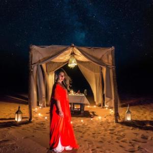 a woman in a red dress standing in front of a tent at Family Luxury Glamping in Merzouga +42 photos