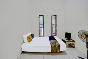 een slaapkamer met een wit bed en een televisie bij OYO LIFE 92077 Tarlo Guest House 3 in Pradahkalikendal