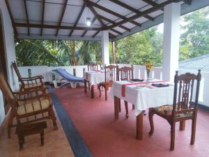 uma sala de jantar com mesas e cadeiras num alpendre em Sahani Villa em Aluthgama