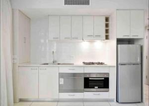 eine Küche mit weißen Schränken und einem Kühlschrank aus Edelstahl in der Unterkunft CBD 1BED/POOL/GYM/SAUNA/ - CLOSE TO EVERYTHING! in Brisbane