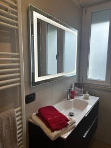 baño con lavabo con espejo y toalla roja en A casa di Rosa, en Tricarico
