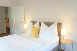 białe łóżko z białymi poduszkami i 2 lampami w obiekcie Schwarzacherhof Pension & Apartments w mieście Schwarzach im Pongau