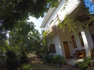 Biały dom z drzewami i roślinami przed nim w obiekcie 20 House Villa w mieście Arugam Bay