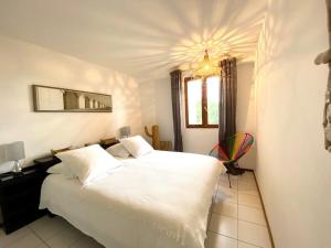 sypialnia z dużym białym łóżkiem i żyrandolem w obiekcie villa d'exception avec piscine , au bord de la mer w Hyères