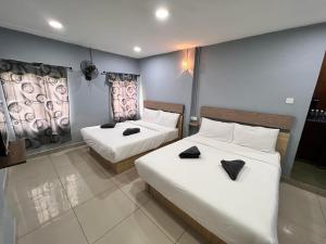 um quarto com 2 camas com lençóis brancos e saltos pretos em Hotel Yasmin em Brinchang