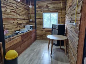 cocina con paredes de madera, mesa y fregadero en สายฝนการ์เด้น, en Ban On Luai