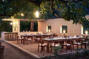 a restaurant with wooden tables and chairs at night at Bagh Tola, Bandhavgarh Tiger Reserve in Tāla