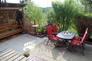 a patio with a table and four red chairs at Ferienhaus Bergblick am See in Waldkirchen