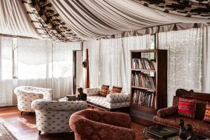 a living room with two chairs and a book shelf at Bagh Tola, Bandhavgarh Tiger Reserve in Tāla