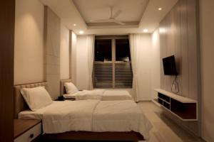 1 dormitorio con 2 camas y TV. en The Presidential Suites, en Bhuj