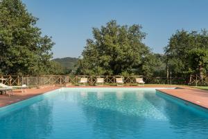 a large swimming pool with chairs and a fence at Agriturismo L'Incrociata in Bucine