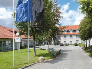 eine Straße mit einer blauen Flagge vor einem Gebäude in der Unterkunft Victor's Residenz-Hotel Teistungenburg in Teistungen