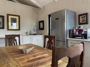 a kitchen with a wooden table and a refrigerator at Vredenbosch Hoekwil in Wilderness