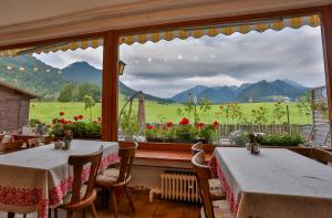 un ristorante con due tavoli e una grande finestra di Pension Rauschberghof a Ruhpolding