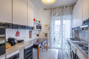 a kitchen with white cabinets and a large window at Hostel Art in Trieste