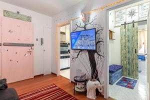 - un salon avec une télévision et un arbre sur le mur dans l'établissement Hostel Art, à Trieste
