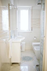 La salle de bains blanche est pourvue d'un lavabo et de toilettes. dans l'établissement Garden Apartment, à Pescara