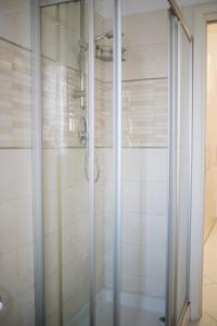 La salle de bains est pourvue d'une douche avec des portes en verre. dans l'établissement Garden Apartment, à Pescara