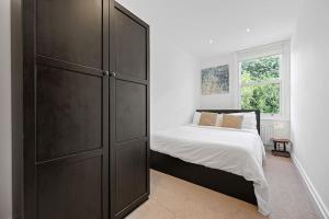 a bedroom with a large black cabinet next to a bed at Ealing Broadway - Lovely 2-bedroom flat with offstreet parking in Ealing