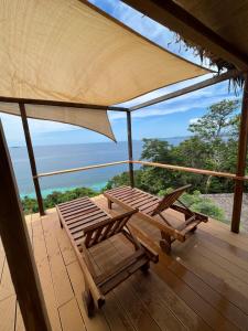 una terraza con 2 sillas y una sombrilla en Canopee Lodge en Nosy Komba