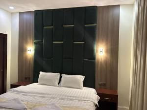 a bedroom with a large bed with a green headboard at Fakher Yanbu Hotel in Yanbu