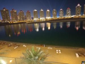 a large body of water with a city at night at Luxury Sea View Apartment with Amazing Amenities at Pearl Qatar in Doha