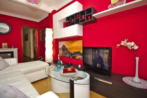 sala de estar roja con sofá blanco y TV en CLEOPATRA APARTMENT, en Alicante