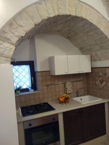 uma cozinha com um arco de pedra sobre um fogão e lavatório em Soggiornare In Centro em Alberobello