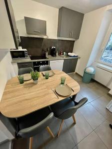 uma cozinha com uma mesa de madeira e algumas cadeiras em Appartement le Rhôn'ain - Vue Rhône - Lit Queen size em Bellegarde-sur-Valserine