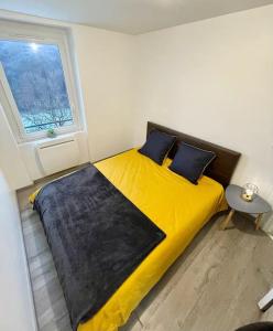 um quarto com uma cama amarela e uma janela em Appartement le Rhôn'ain - Vue Rhône - Lit Queen size em Bellegarde-sur-Valserine