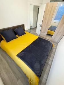 Un dormitorio con una gran cama amarilla con almohadas azules en Appartement le Rhôn'ain - Vue Rhône - Lit Queen size, en Bellegarde-sur-Valserine