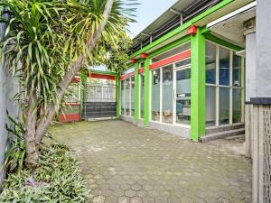 un edificio verde con una palmera delante en OYO 92086 Fun Guesthouse Syariah, en Mojokerto