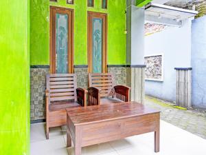 una mesa, 2 sillas y una pared verde en OYO 92086 Fun Guesthouse Syariah, en Mojokerto