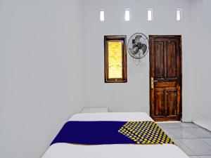 1 dormitorio con 1 cama con manta amarilla y azul en OYO 92086 Fun Guesthouse Syariah, en Mojokerto