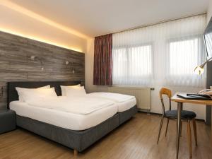 a bedroom with a bed and a table and a desk at Hotel & Wirtshaus Hansen in Bergisch Gladbach