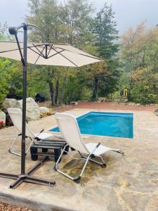 Nevados de Chillan的住宿－Black Domes，游泳池旁的两把椅子和一把遮阳伞