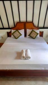1 cama con 2 almohadas y 2 toallas. en Meno Lodge, en Gili Meno