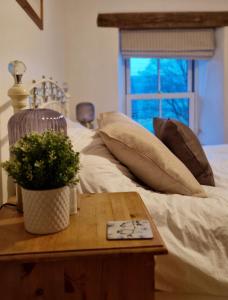 um quarto com uma cama com almofadas e uma mesa em Cringley Cottage em Askrigg