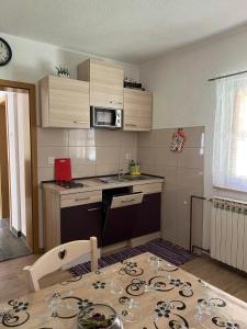 a small kitchen with a table and a microwave at Apartments Marija in Vrelo Koreničko