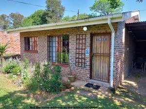 a brick house with a door and a porch at Rustique in Graskop
