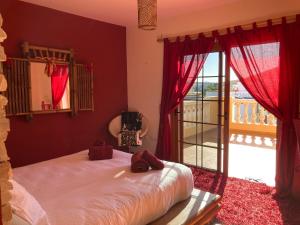 1 dormitorio con 1 cama con cortinas rojas y balcón en Villa Ingrid. Piscina exterior., en Las Playitas