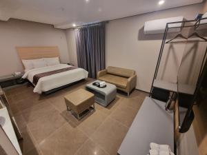 Habitación de hotel con cama y silla en Yeoubi Hotel, en Jinju