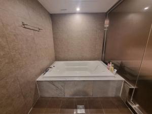 uma banheira na casa de banho com um chuveiro em Yeoubi Hotel em Jinju