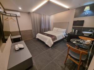 um quarto de hotel com uma cama e uma mesa e cadeira em Yeoubi Hotel em Jinju