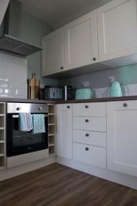 a kitchen with white cabinets and an oven at Rooftops in Louth