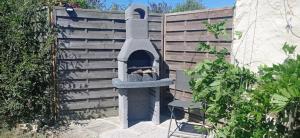a outdoor oven sitting next to a wooden fence at Le Fry Holiday Gite in Lithaire