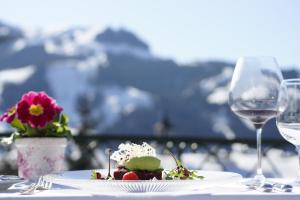 a table with a plate of food and two wine glasses at Relais & Châteaux Hotel Tennerhof in Kitzbühel +94 photos